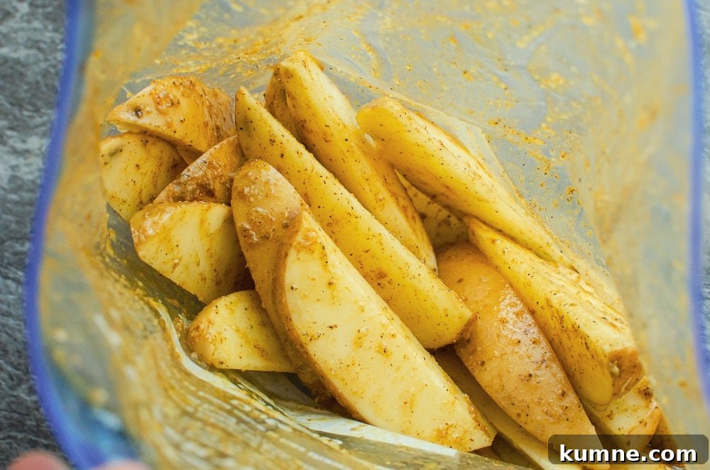 Potato wedges in a sandwich plastic bag being coated in the curry mix