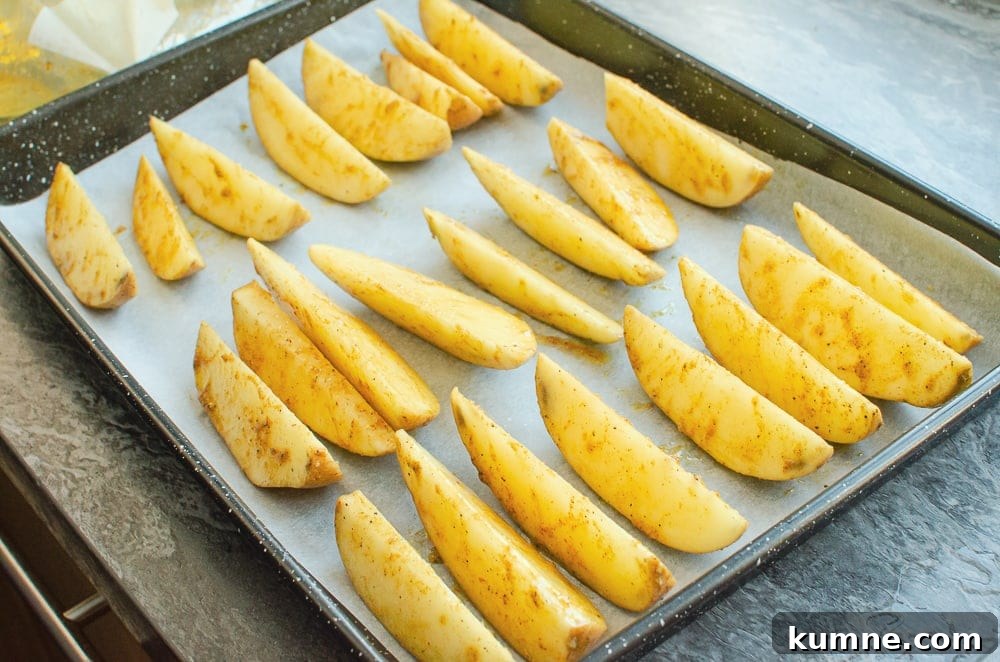 Potato wedges on a baking tray lined with white parchment paper