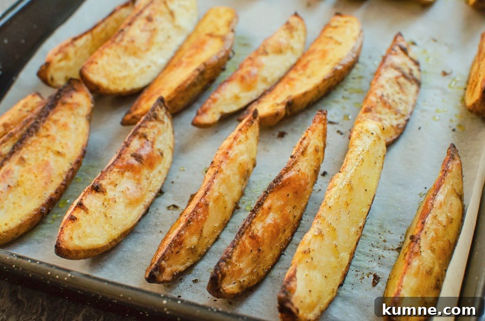 Potato wedges cooked on a baking tray lined with white parchment paper