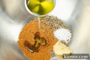 Garam masala, pepper, salt, garlic puree and olive oil in a silver mixing bowl