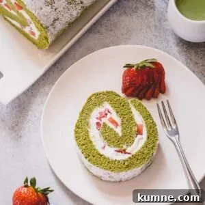 Matcha Swiss Roll Cake Recipe — Light, Fluffy Japanese Roll 9 A slice of strawberry matcha roll cake on a white serving plate.