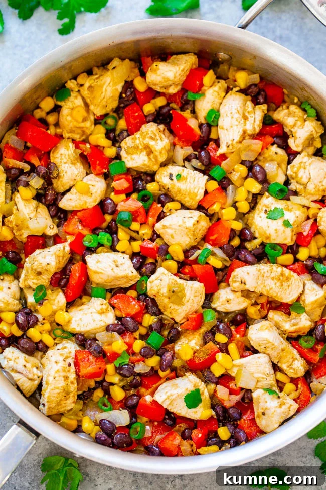 Chicken and vegetable stir-fry with corn, black beans, and red peppers in a skillet.