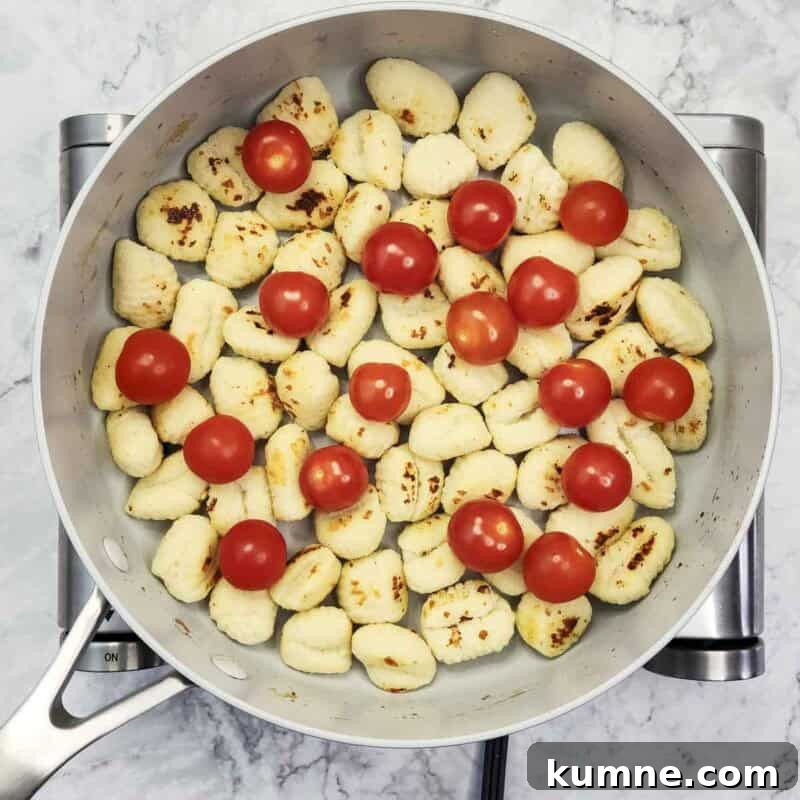 Add cherry tomatoes to the pan, cover briefly so tomatoes split and gnocchi steam through.