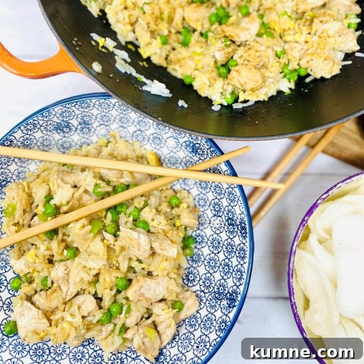 Blue and white bowl of chicken fried rice with peas and chopsticks