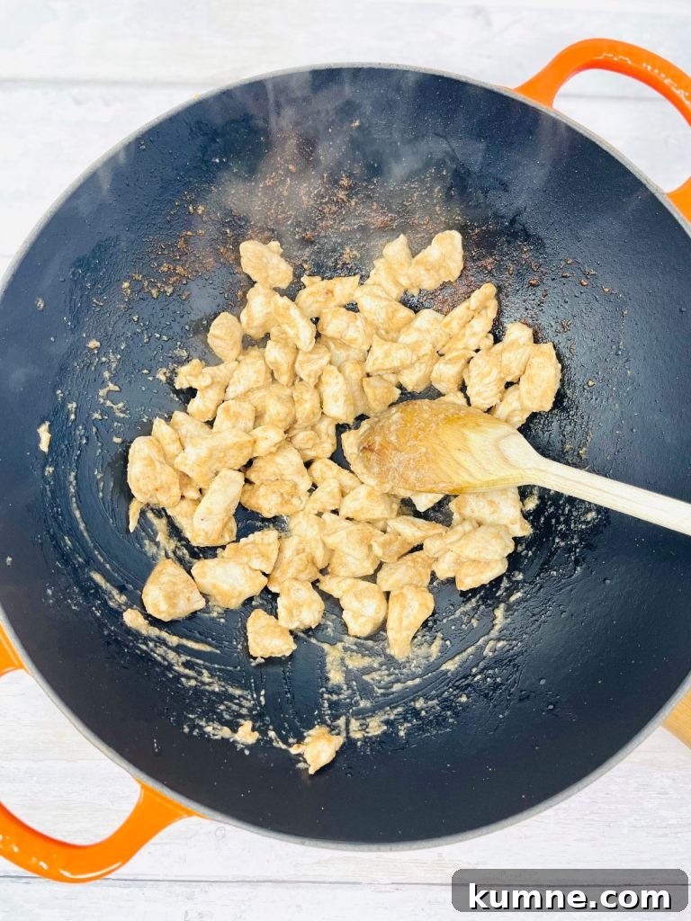 Chicken Fried Rice Recipe: Quick Homemade Takeout-Style Meal 4 Wooden spoon stirring cooked chicken in a pan