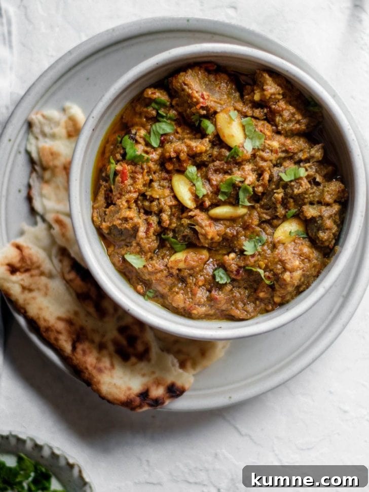 Pakistani Beef Curry (Stew) in a bowl on top of a plate with naan 