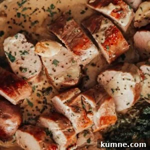 Pork tenderloin in a pan with sauce and herbs.