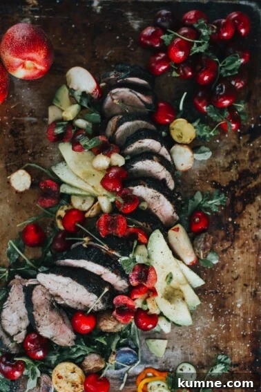 Close up of pork tenderloin with bright cherries and avocado slices