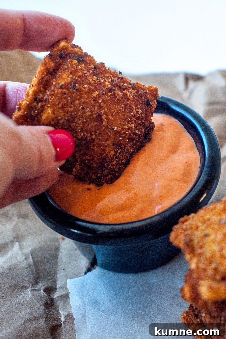Dipping a delicious Crispy Ravioli into an easy Roasted Red Pepper Sauce.