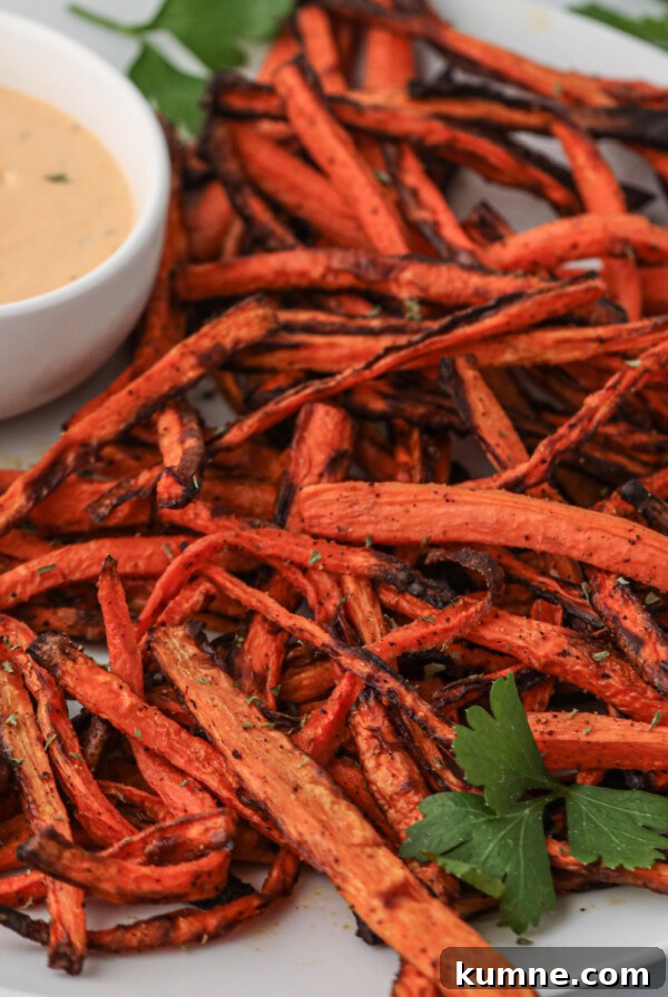 Carrot fries made in the air fryer and served on a plate with dipping sauce.