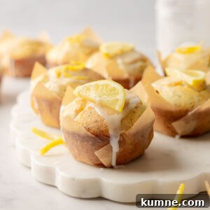 Gluten-Free Lemon Poppy Seed Muffins Recipe for Moist, Zesty Bites 11 Lemon poppy seed muffins with glaze and lemon slice garnish on marble board.