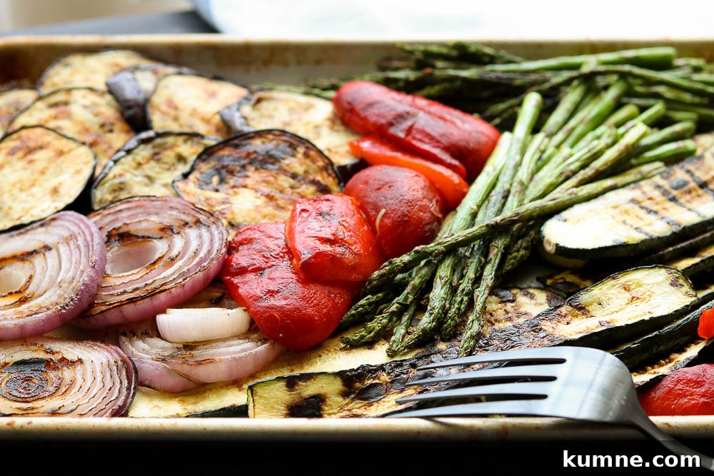 horizontal view of grilled balsamic vegetables on sheet pan with serving fork 