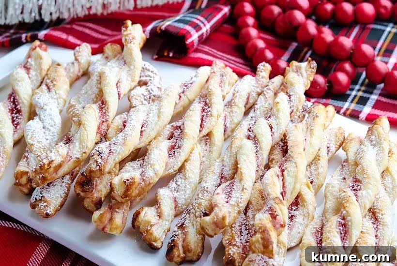 Close up of raspberry pastry twists on a white platter with red decor in the background.