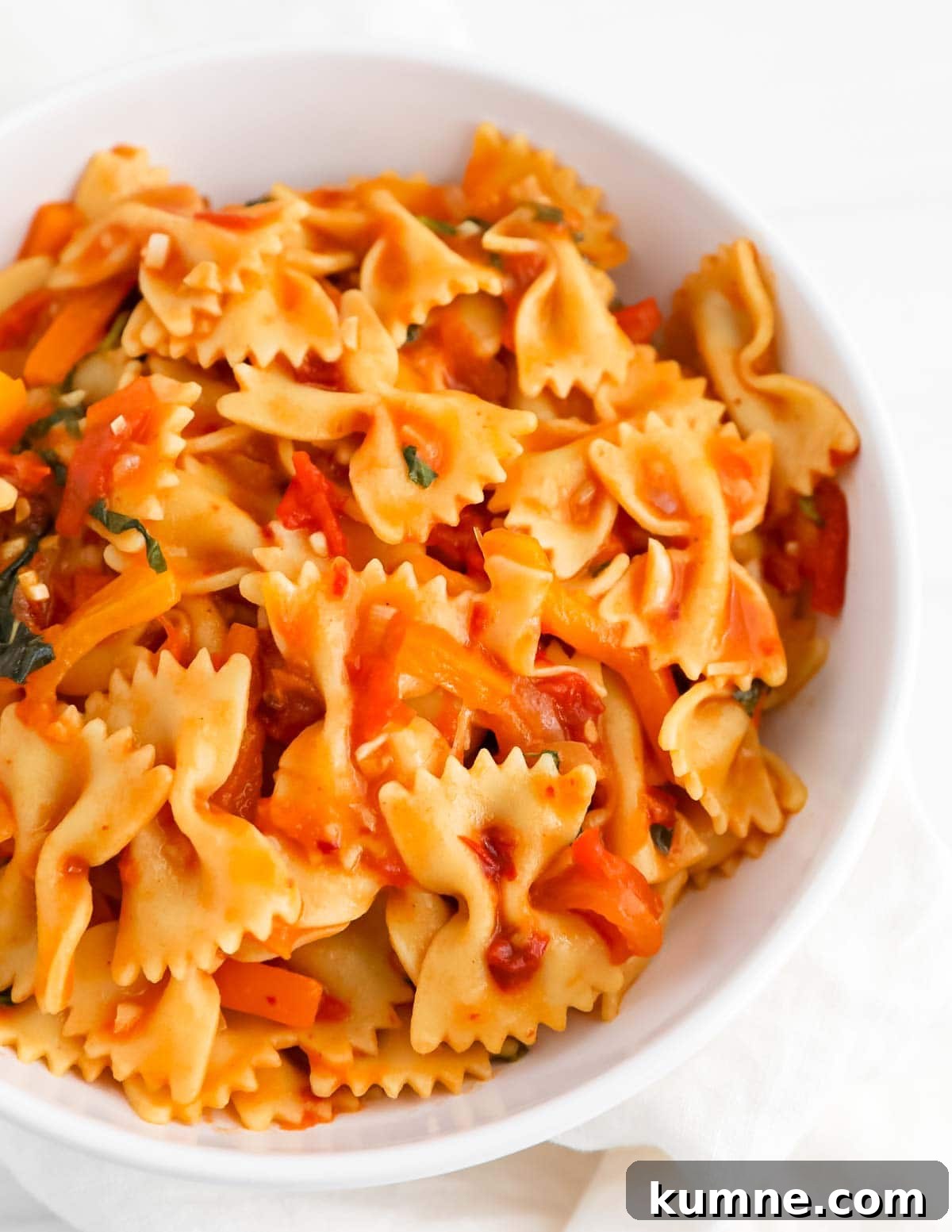 A close-up image of bowtie pasta covered in a red sauce.