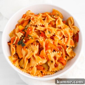 Bowtie pasta tossed in a thick red sauce in a white bowl.