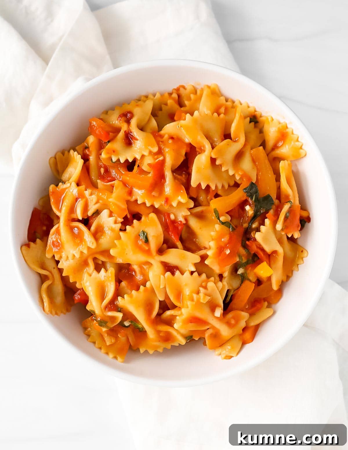 An overhead image of pasta with a vegetable red sauce in a white bowl.