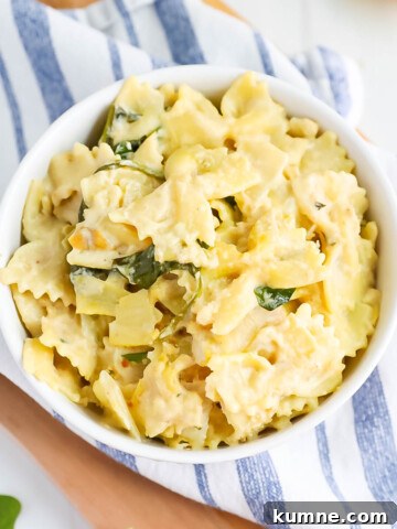 Creamy white sauce pasta with spinach in a white bowl.