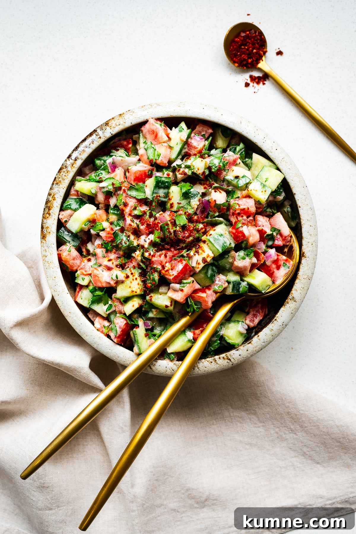 Tahini salad made from tomato, cucumber, red onion and parley with a lemon tahini sauce topped with Aleppo pepper flakes.