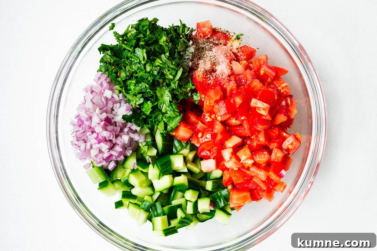 Cubed israeli salad ingredients in a mixing bowl.