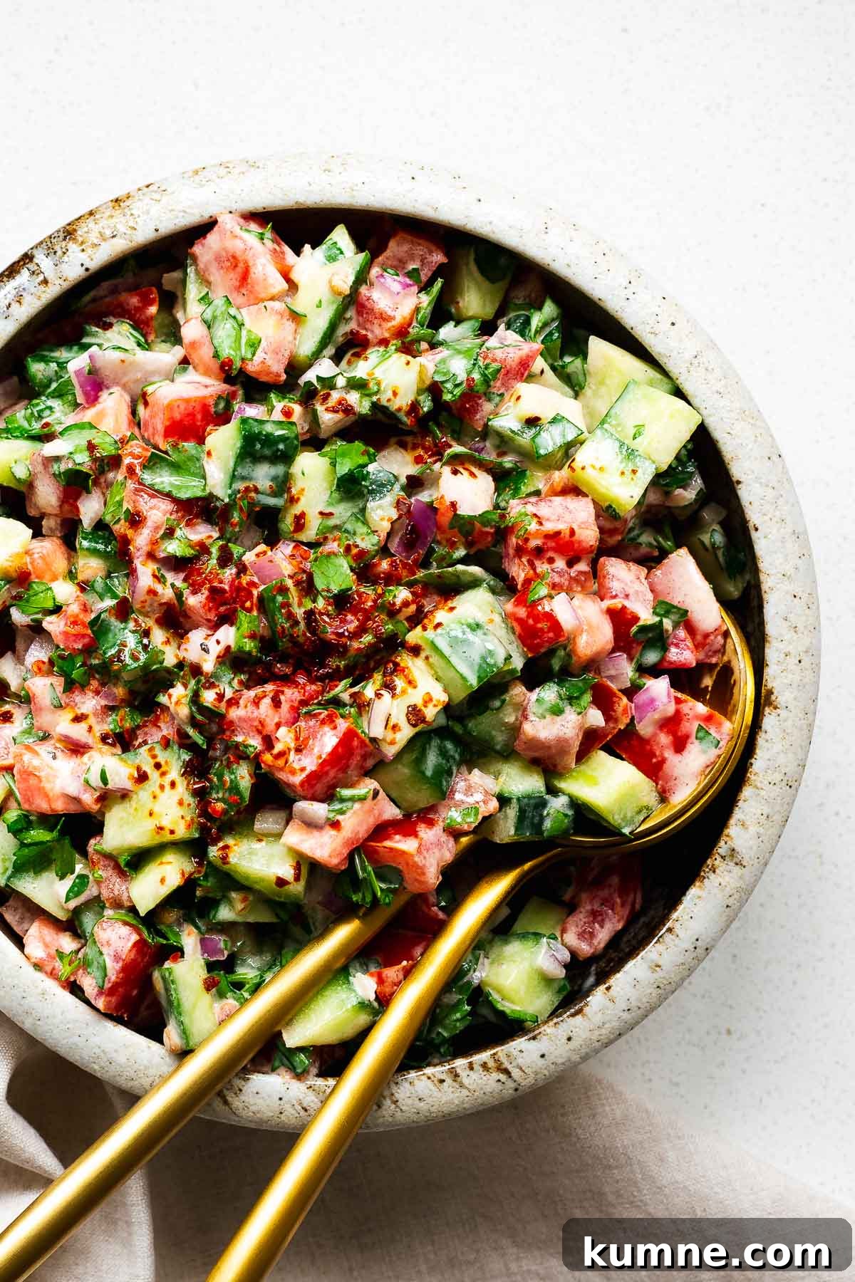 Middle Eastern tahini salad in a bowl with gold serving spoons.