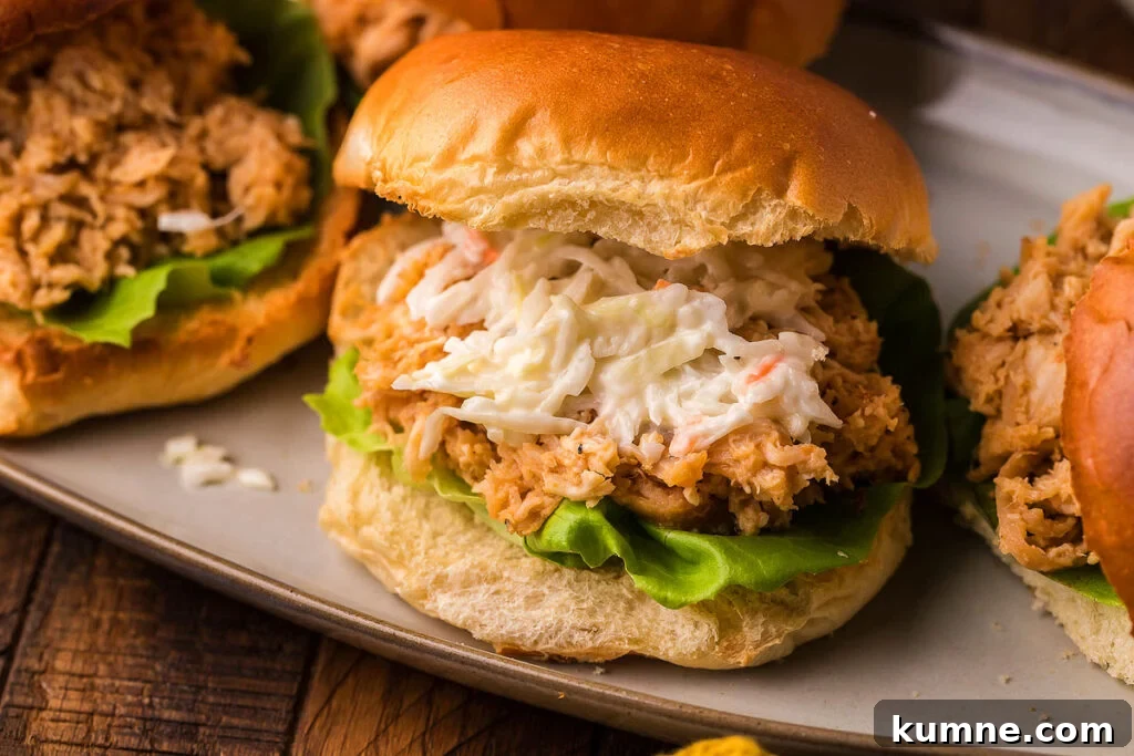 A pulled chicken sandwich with coleslaw on a plate.