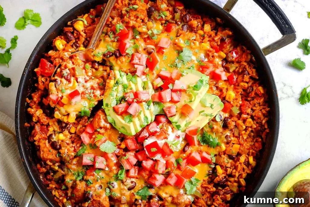 A skillet with a chicken fiesta dish with avocados on top.