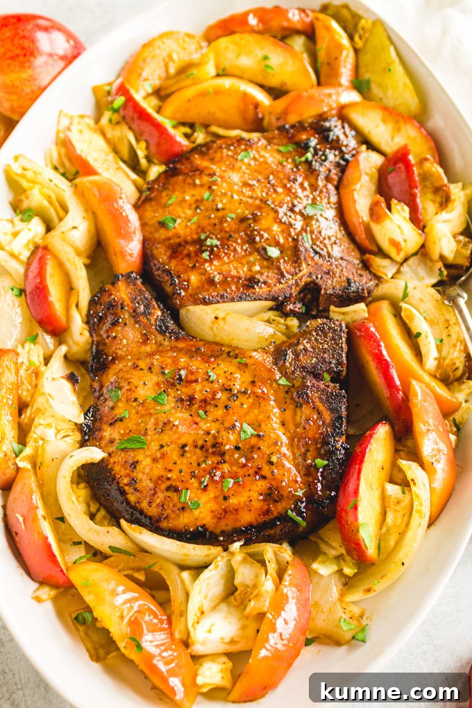 maple pork chops on platter with cooked apple slices and cabbage, at an angle.