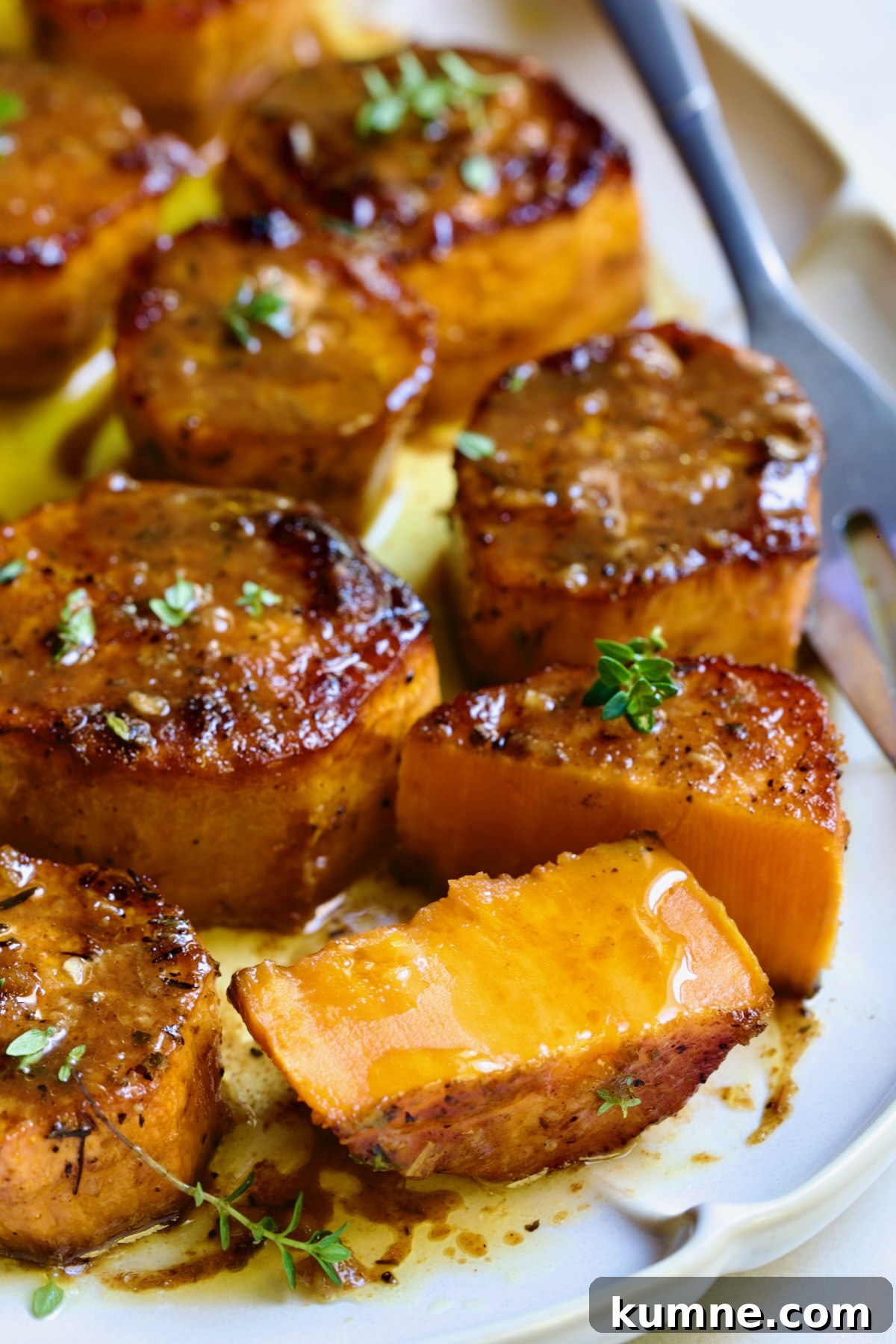 Fondant Sweet Potatoes garnished with fresh thyme on white oval platter with one cut in half.
