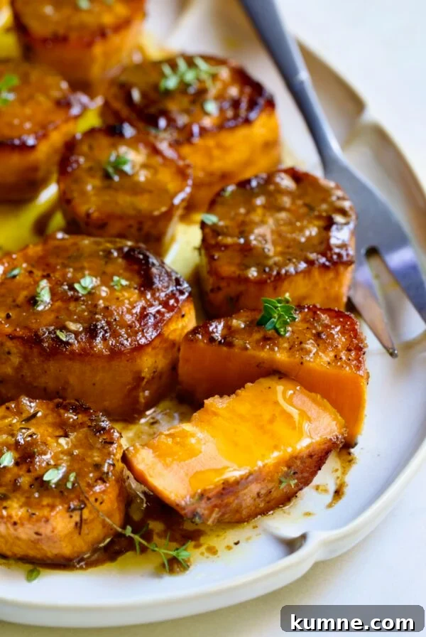 Fondant Sweet Potatoes garnished with fresh thyme on white oval platter with one cut in half.