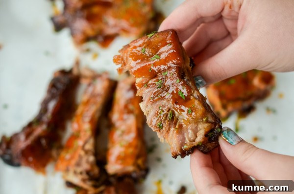 This image shows someone about to eat a slow cooker baby back ribs with apple barbecue sauce.