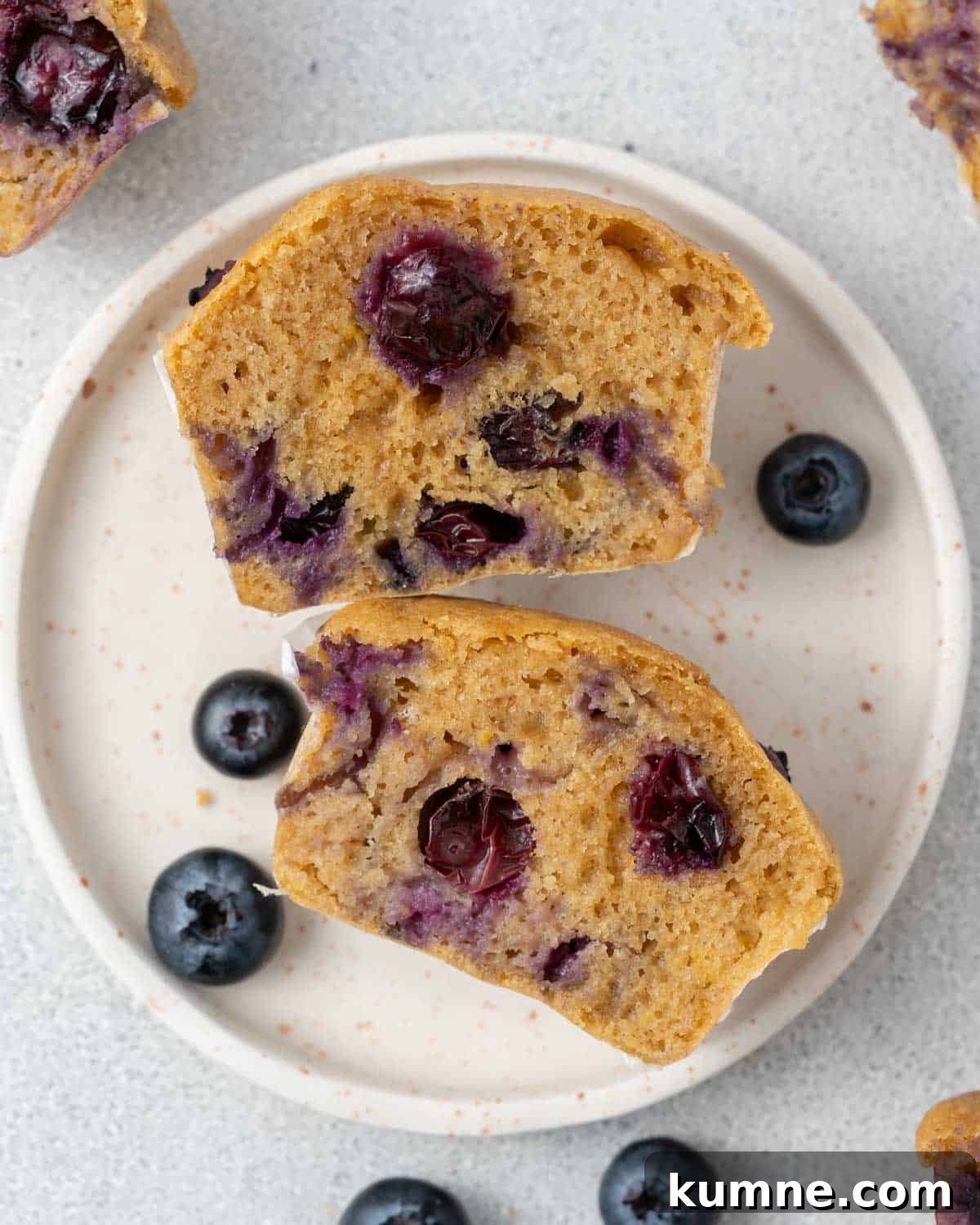 a blueberry muffin sliced in half on a plate.