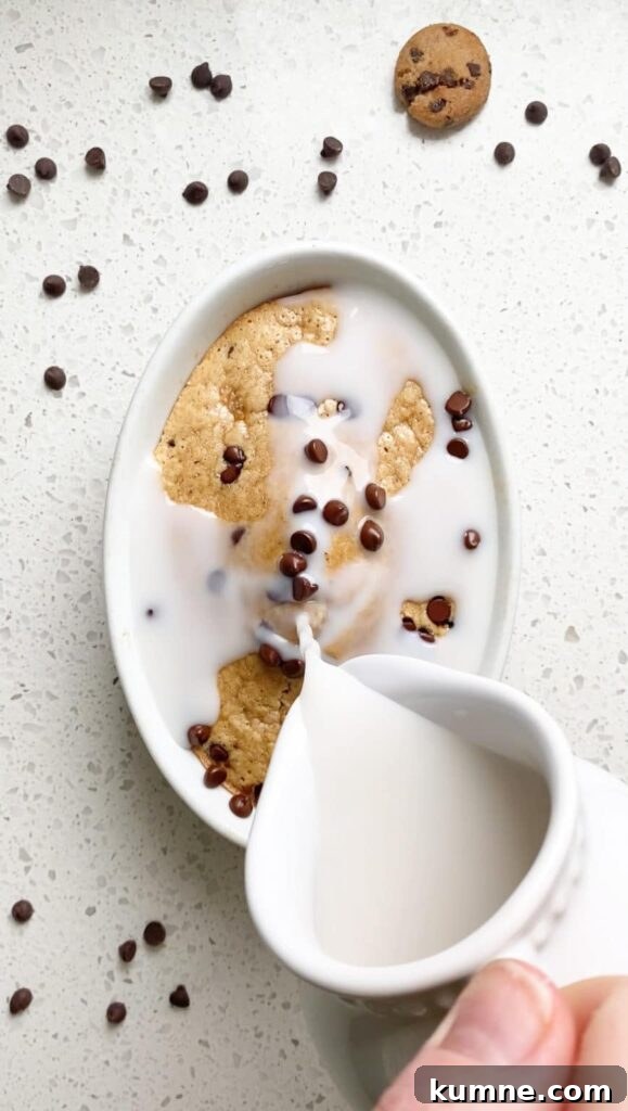 High-Protein Cookie Dough Baked Oats — Single-Serve (38g) 3 almond milk being poured over warm cookie dough baked oats in casserole dish