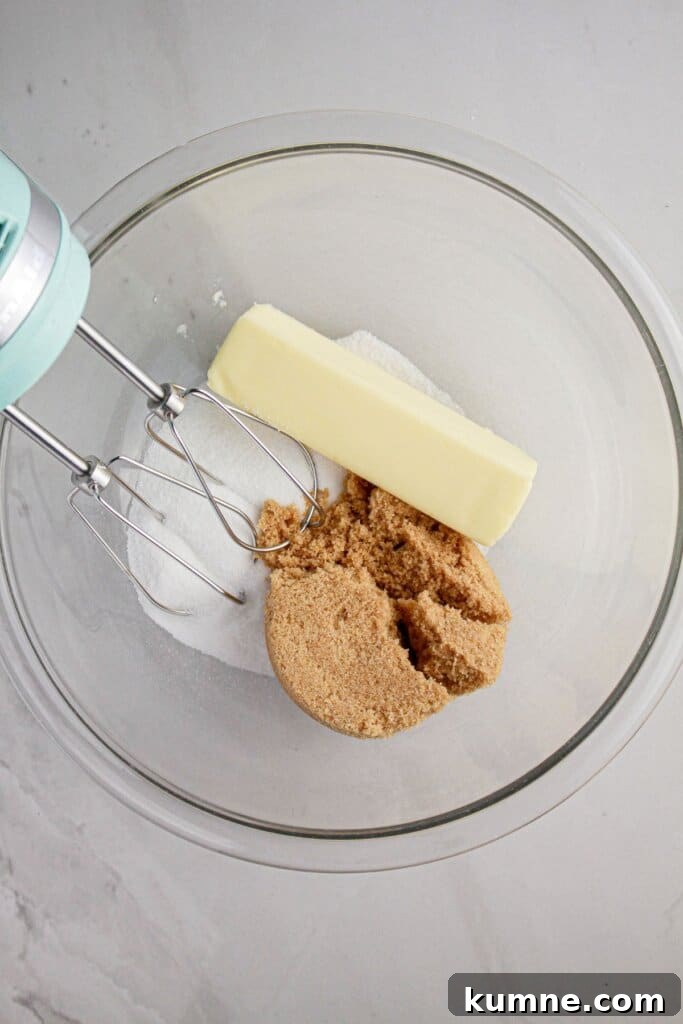 Butter, brown sugar, and granulated sugar being mixed in a glass bowl.