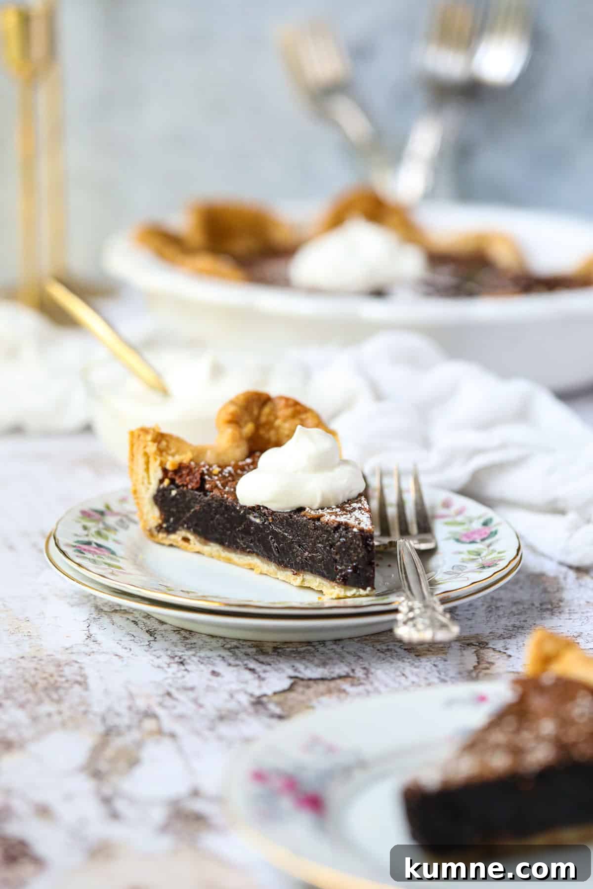 A slice of chocolate chess pie on a white dessert plate with a silver fork.