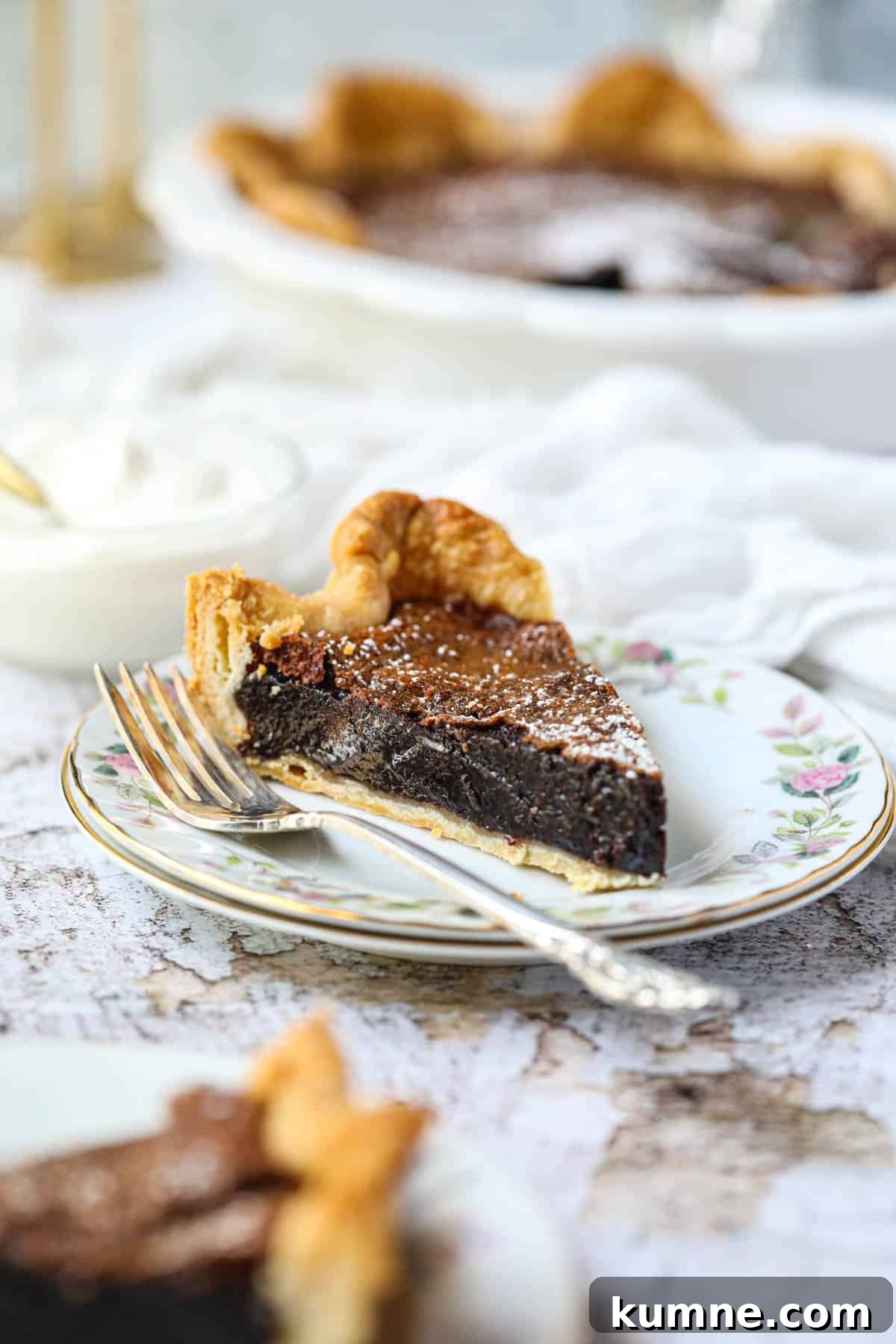 A slice of chocolate chess pie on a white dessert plate with a silver fork.