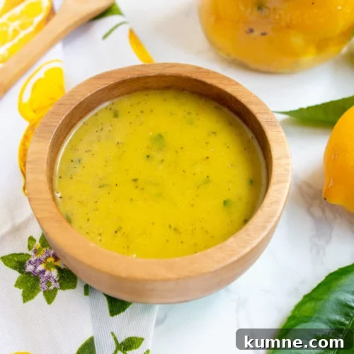 Preserved lemon vinaigrette in wooden bowl with preserved lemons on the side.