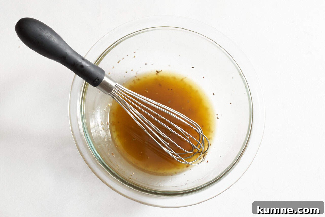A bowl of red wine vinaigrette dressing with a whisk in it.