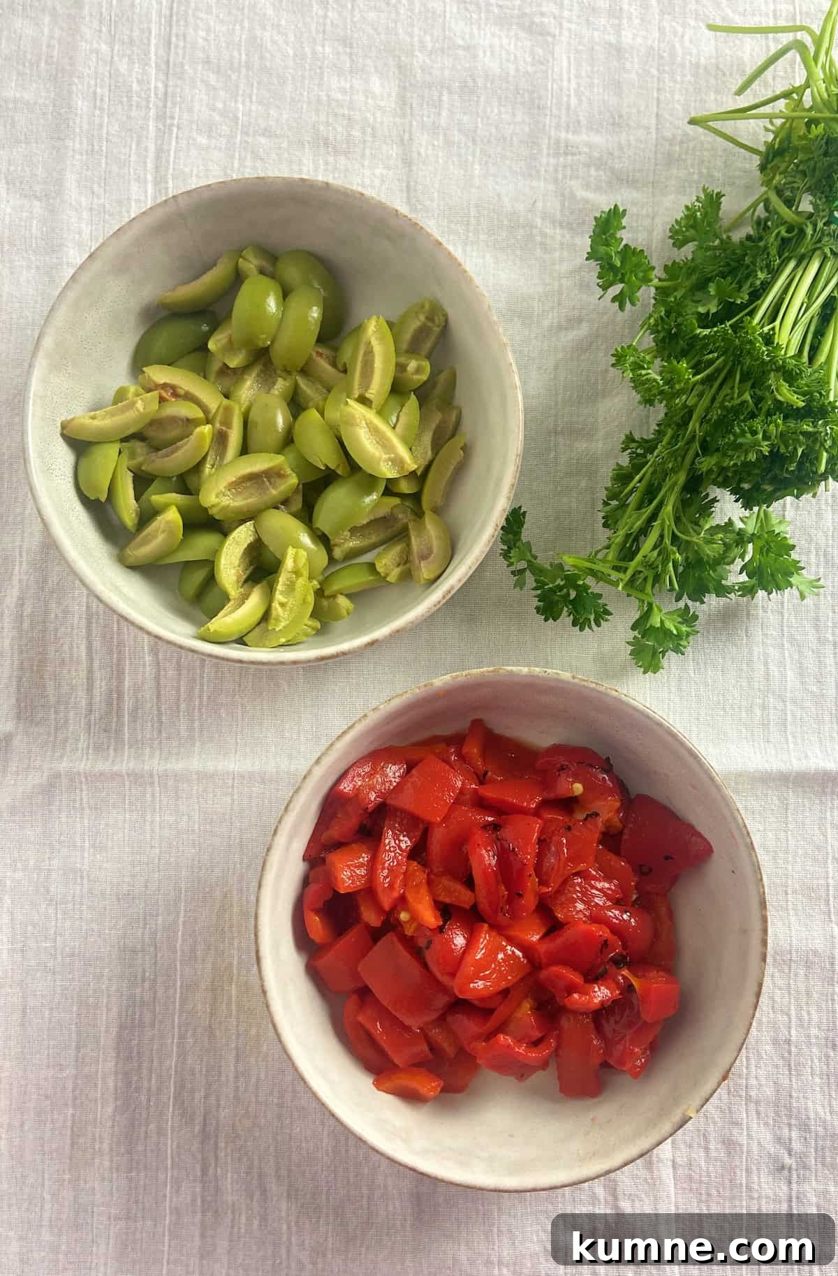 Sliced olives and diced roasted red peppers in bowls.