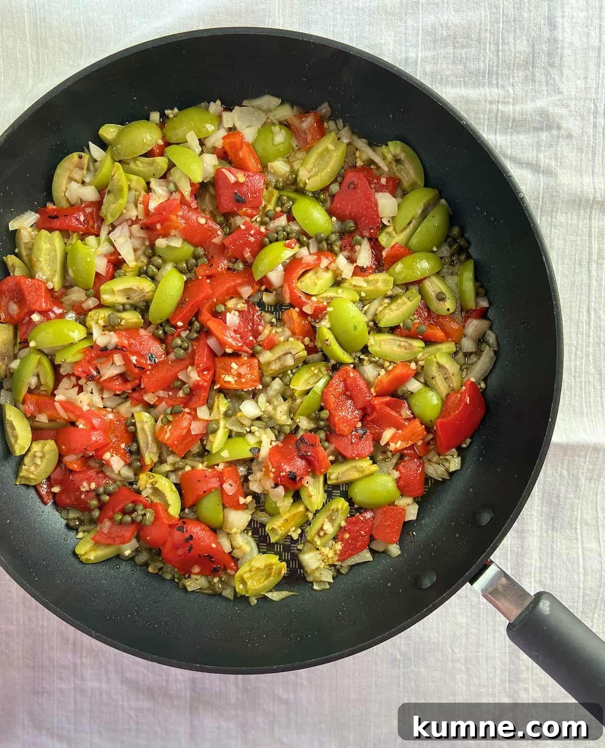 Sauteed roasted red peppers, olives, garlic and capers in saucepan.