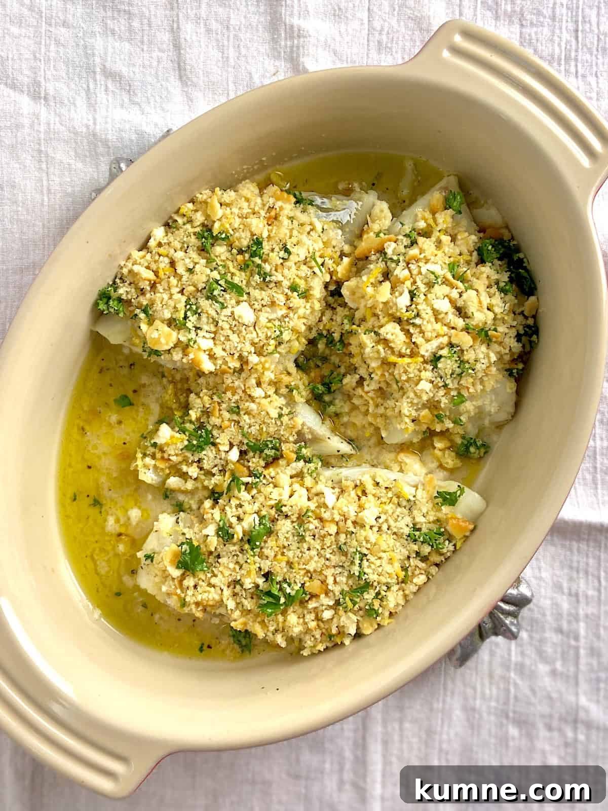 Baked cod with breadcrumbs on top in baking dish.