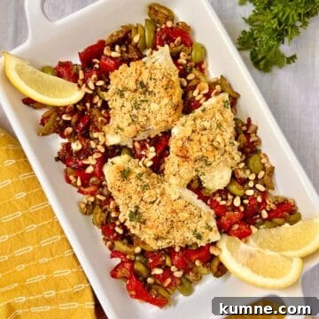 Sicilian baked cod with garlic breading resting on a bed of roasted red peppers and olives.