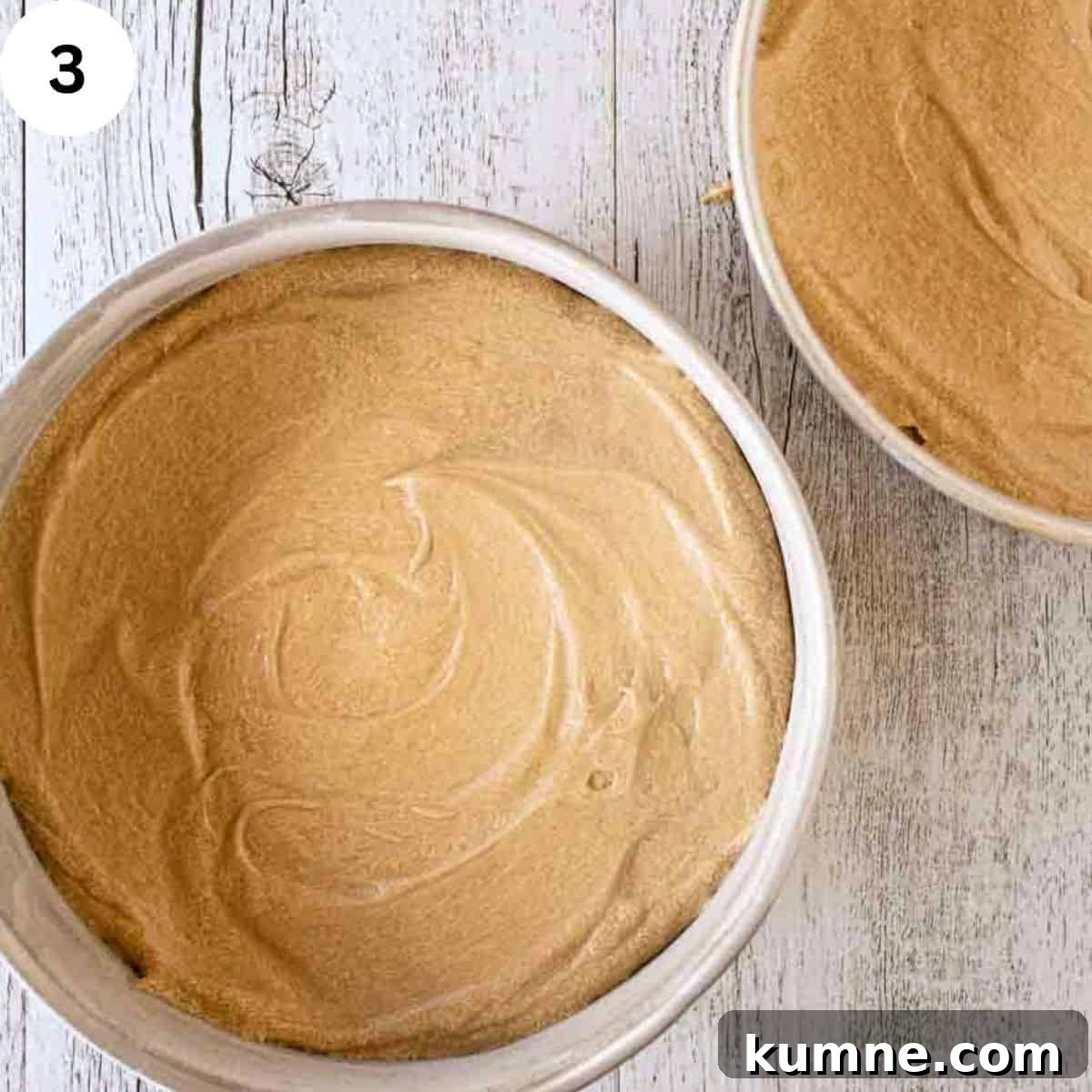 Cake batter divided into two round cake pans.