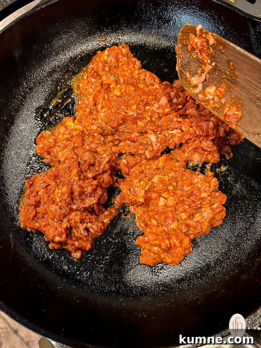 Browning ground pork chorizo in a skillet.