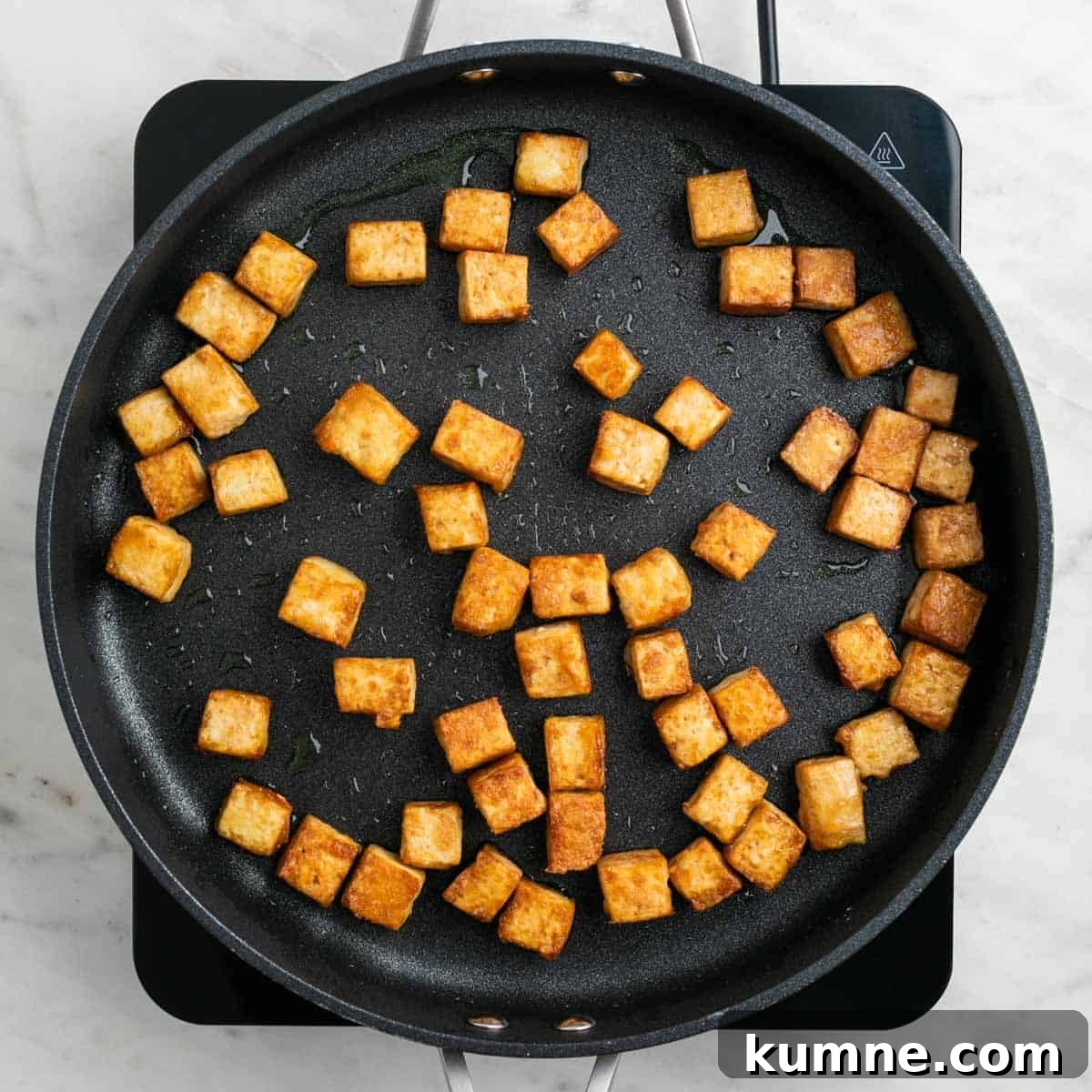 Tofu cooking in a pan until golden and crispy