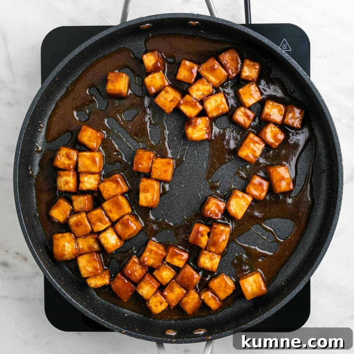 Crispy tofu cooking in a pan with sauce